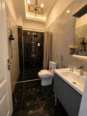Une salle de bain moderne avec une douche à parois de verre, des toilettes blanches et un meuble-lavabo.