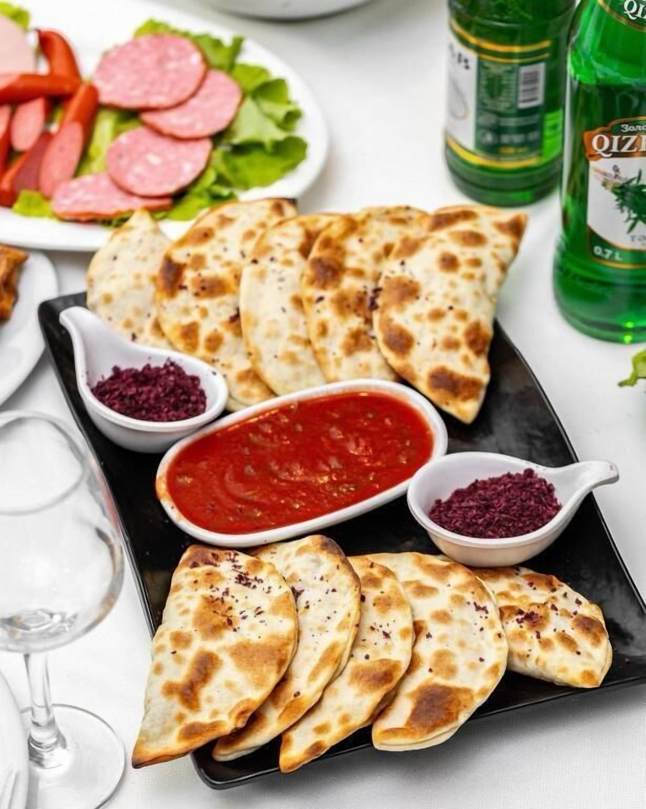 A plate of flatbread with two dipping sauces and a side salad.