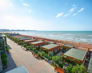 Un hotel costero con varias habitaciones, un paseo pavimentado y vistas a la playa.