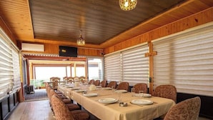 A long dining table set with chairs, a wooden ceiling, and a view through a window. - Gallery & Sea Hotel (Sumqayit)
