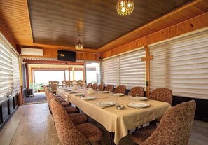 A long dining table set with chairs, a wooden ceiling, and a view through a window. - Gallery & Sea Hotel (Sumqayit)