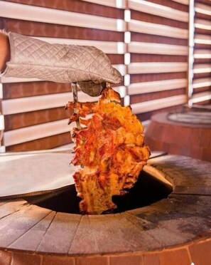 A hand holding a large, grilled pineapple. - Gallery & Sea Hotel (Sumqayit)