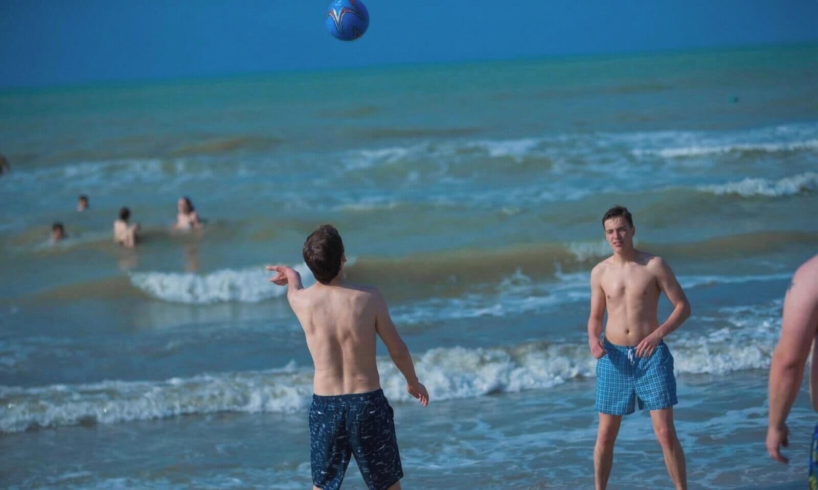Escena de playa con gente jugando al voleibol.