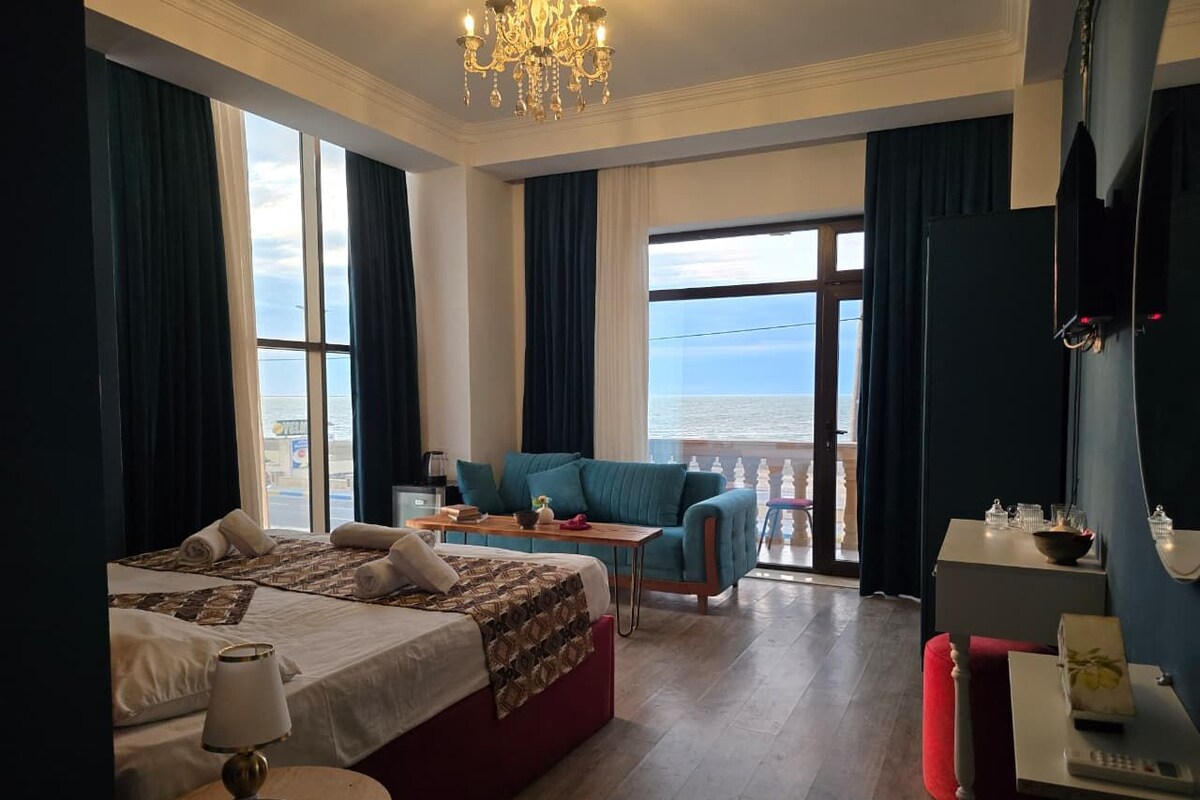 A hotel room with a bed, a sofa, a table, and a balcony with a view.