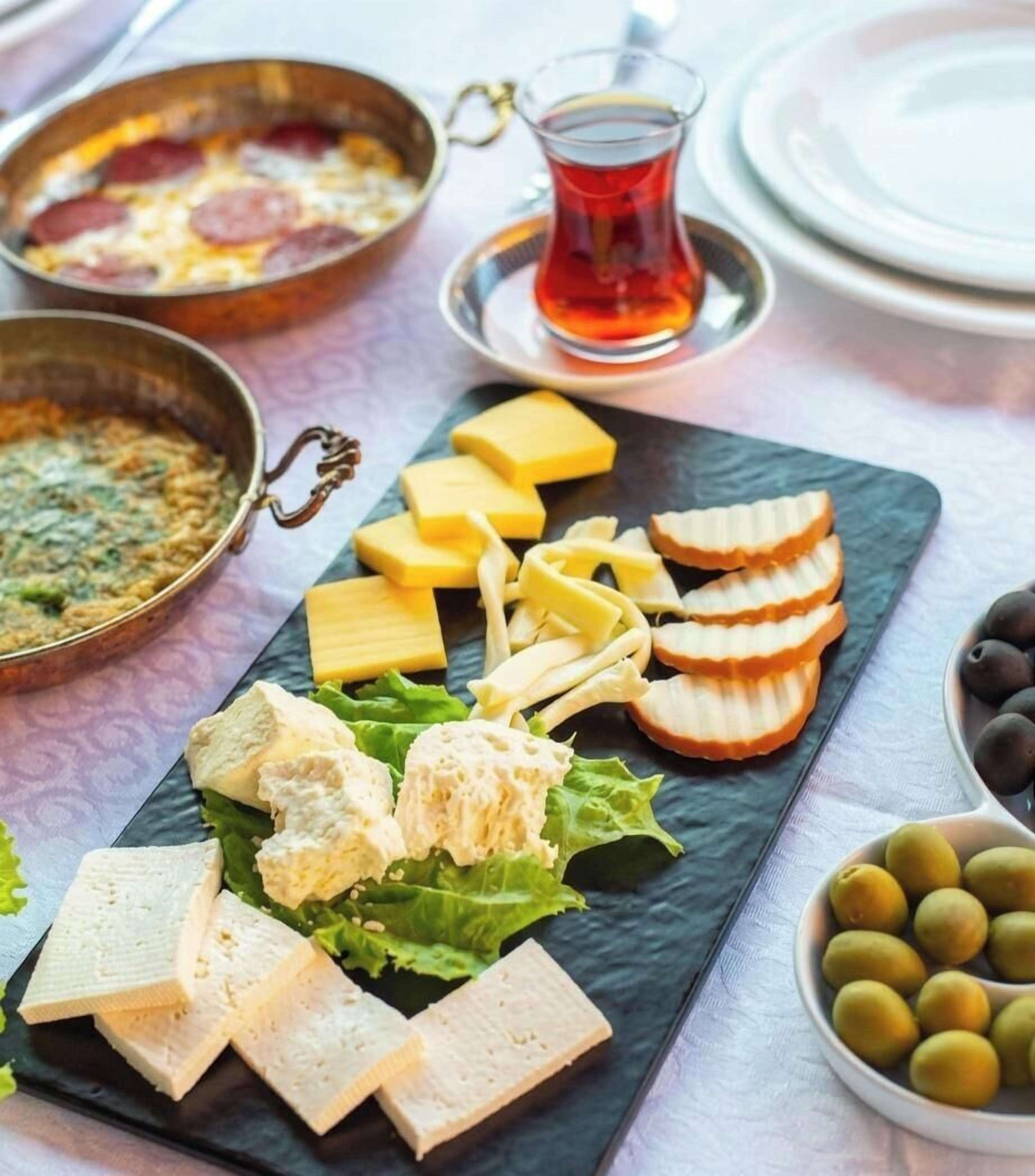 Una mesa con diversos alimentos, como queso, pan y aceitunas.