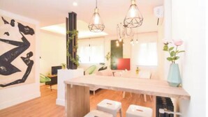 Un interno moderno con un tavolo da pranzo in legno, lampade a sospensione e un grande dipinto astratto.