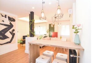 Ein modernes Interieur mit einem Holztisch, Pendelleuchten und einem großen, abstrakten Gemälde.