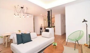 Ein modernes Wohnzimmer mit einem weißen Sofa, einem Esstisch und einem grünen Sessel.