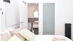 Una camera da letto con un letto, una lampada da comodino, una porta che dà su un bagno e un termosifone.