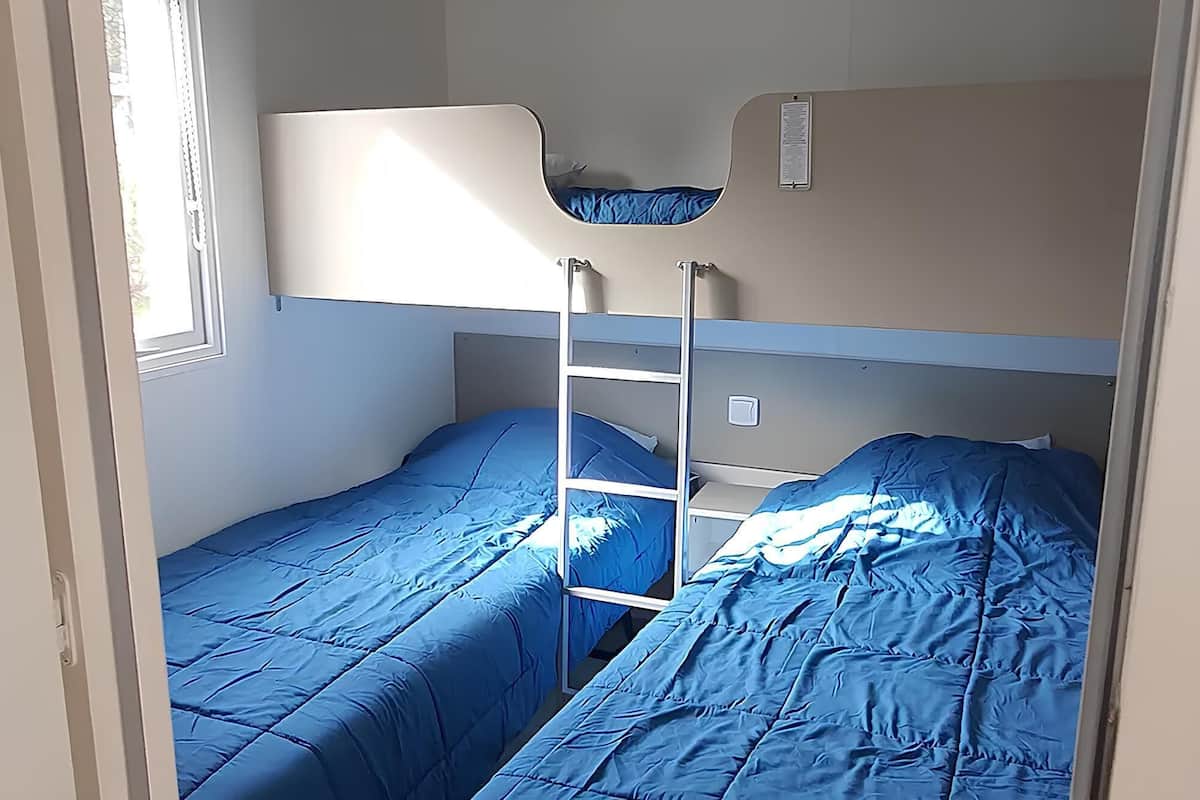 A bunk bed room with a ladder, a window, and a door.