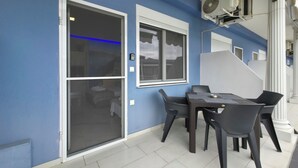 Een kamer met een blauwe wand, een glazen schuifdeur, een tafel met stoelen en een aan de wand bevestigde airconditioner.
