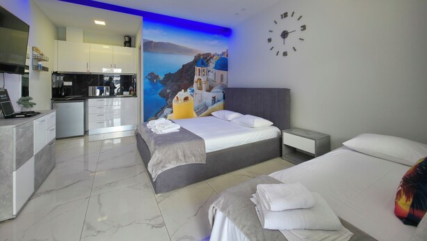 Een moderne hotelkamer met een bed, nachtkastje, keukenhoek en een badkamer.