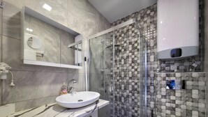 Een moderne badkamer met een glazen douchecabine, een wit wastafelmeubel en een toilet.