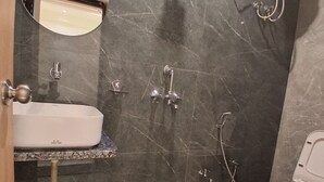 A bathroom with a sink, mirror, toilet, and shower. - Kailas Residency (Varanasi)