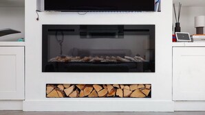 A modern fireplace with a glass front, a mounted television above it, and a white cabinet below. - 
Stylish 2-Bed Split-Level Flat in Shoreditch | Short Let (Up to 1 Month) (London)