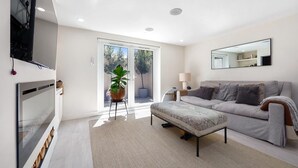 A modern living room with a sofa, a coffee table, a TV, and a potted plant. - 
Stylish 2-Bed Split-Level Flat in Shoreditch | Short Let (Up to 1 Month) (London)