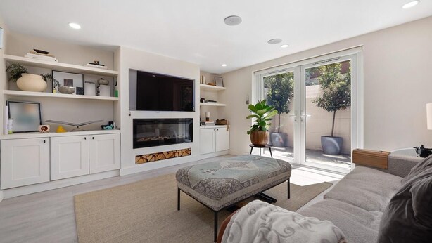 A modern living room with a fireplace, built-in shelves, a flat-screen TV, and a sliding glass door leading to a balcony. - 
Stylish 2-Bed Split-Level Flat in Shoreditch | Short Let (Up to 1 Month) (London)