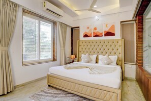 A bedroom with a large bed, a ceiling fan, a window with curtains, and wall art. - Alaya Stays Nest 4BHK villa with Pool  (Lonavala)