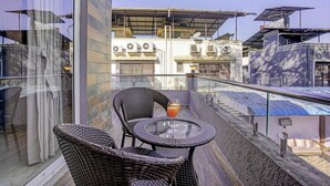 A balcony with wicker furniture, a glass table, and a drink. - Alaya Stays Nest 4BHK villa with Pool  (Lonavala)