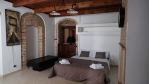 A bedroom with a bed, a bench, a TV, and a decorative wall piece. - Vacation house with Terrace in the historic center of Bernalda, 10 minutes from the sea. (Bernalda)