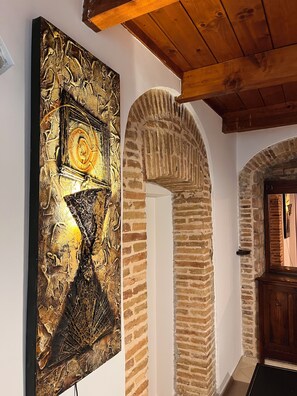 A room with a large abstract painting, a stone archway, and a wooden ceiling. - Vacation house with Terrace in the historic center of Bernalda, 10 minutes from the sea. (Bernalda)