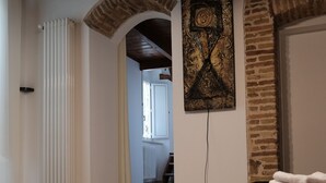 A bedroom with a wooden ceiling, a radiator, a bed, and a brick wall. - Vacation house with Terrace in the historic center of Bernalda, 10 minutes from the sea. (Bernalda)