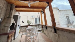 A covered patio area with a wooden ceiling, a white table with chairs, and a view of the surrounding buildings. - Vacation house with Terrace in the historic center of Bernalda, 10 minutes from the sea. (Bernalda)