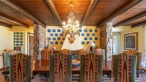 A dining area with a wooden ceiling, stone pillars, and patterned chairs. - Elite Collection Molara Infinity Pool & View (Porto San Paolo)