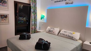 A hotel room with a bed, pillows with text, a nightstand, a wall with a quote, and a window with a view. - Luxury Apartment Very Close to the C.C. Yumbo with 2 King Size Beds 200x200cm (Maspalomas)