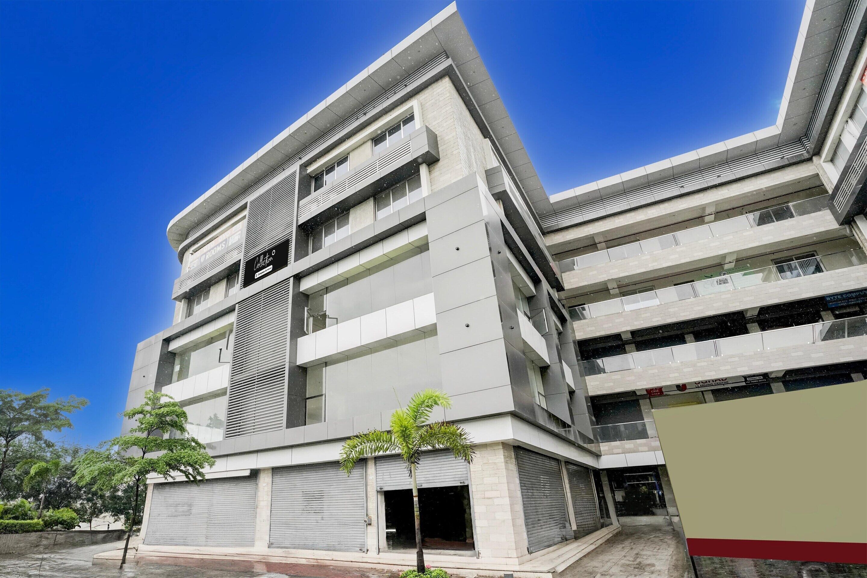 Un edificio de varios pisos con un diseño arquitectónico moderno, que combina materiales como vidrio y hormigón, y un techo plano.
