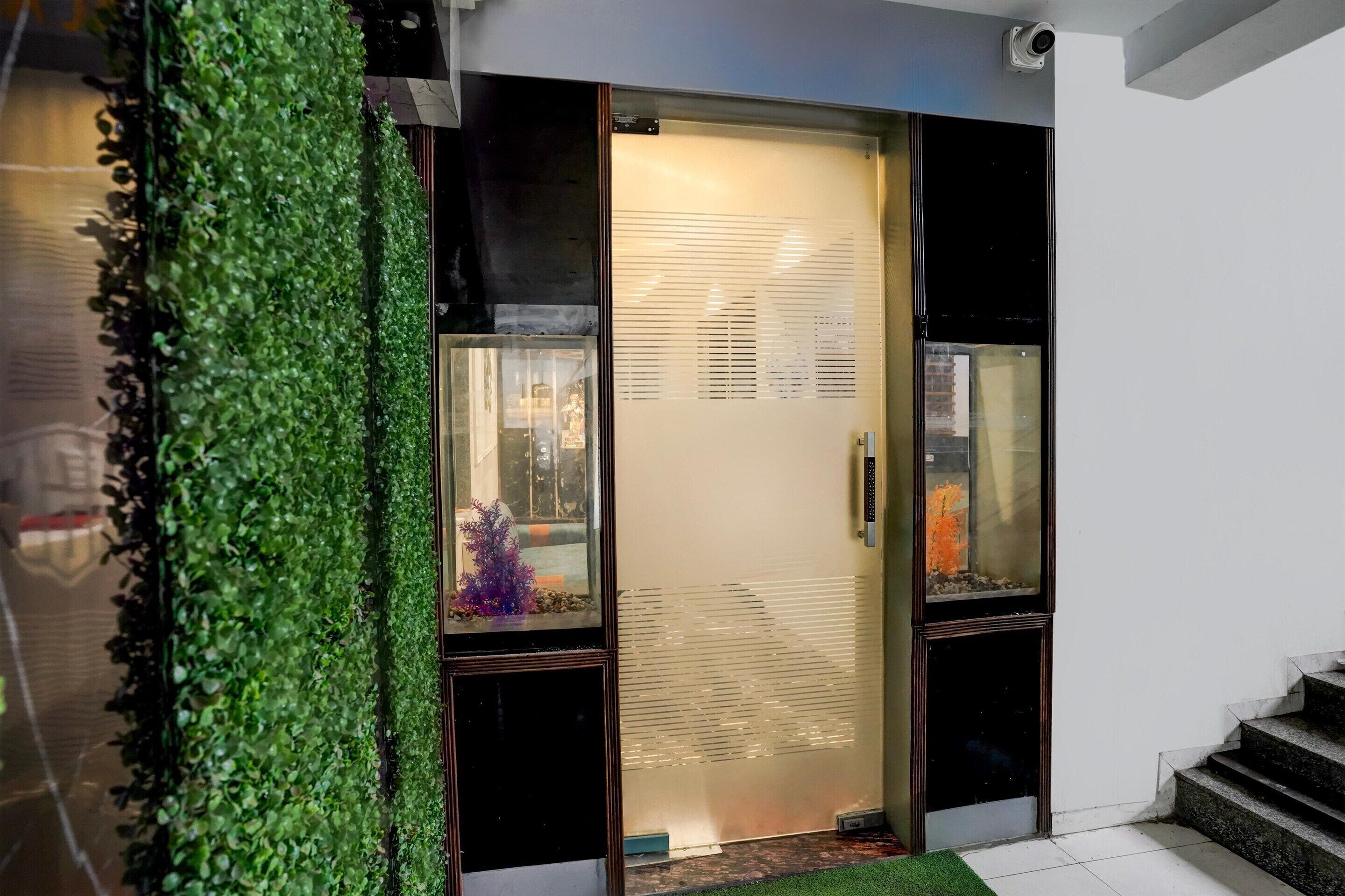 A modern entrance with a glass door, a green wall, and a staircase.