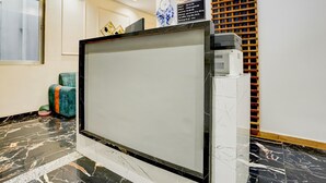 A reception desk with a digital screen, a reception area with a check-in counter, and a wall-mounted display. - Deluxe Room Adajan Sky Palace (Surat)