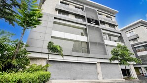A modern multi-story building with a flat facade, large windows, and a sign indicating a business establishment. - Deluxe Room Adajan Sky Palace (Surat)