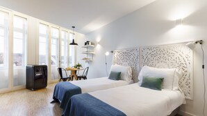 Une chambre d’hôtel avec deux lits, un bureau, une chaise, un réfrigérateur et une tête de lit décorative.