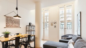 Un coin repas avec une table en bois, des chaises noires, une plante en pot et une carte accrochée au mur.
