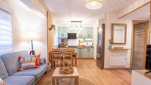 A compact living space with a sofa, dining table, kitchen area, and a mirror. - Apartment with parking included (Gijon)