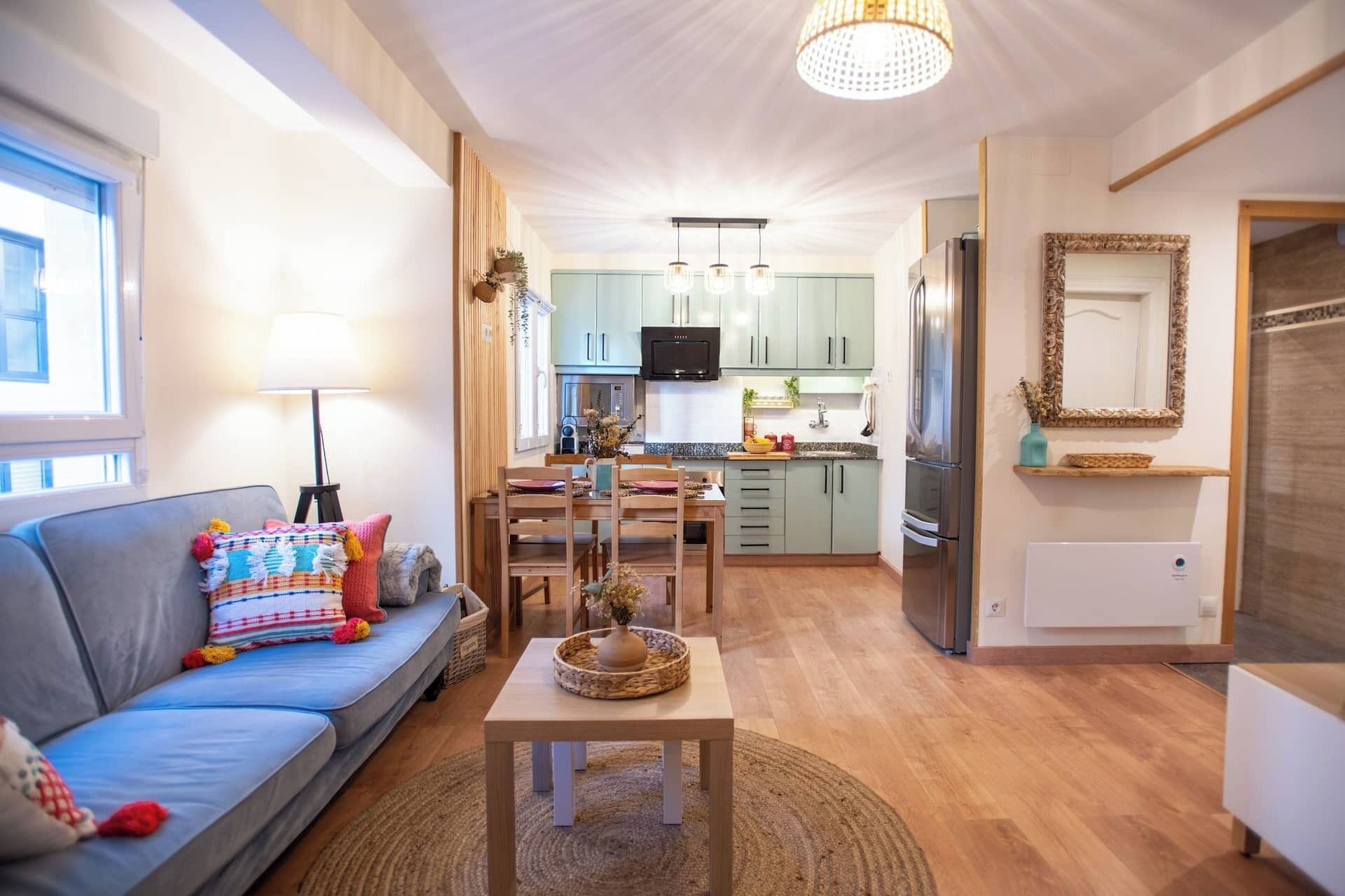 Een moderne woonkamer met een bank, een eettafel en een keukenhoek met een koelkast en magnetron.