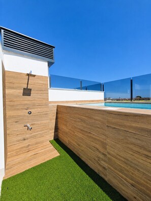 A modern outdoor pool area with a wooden deck and a clear blue sky. - Casa Aruna | Private Pool & Rooftop Terracel (San Pedro del Pinatar)