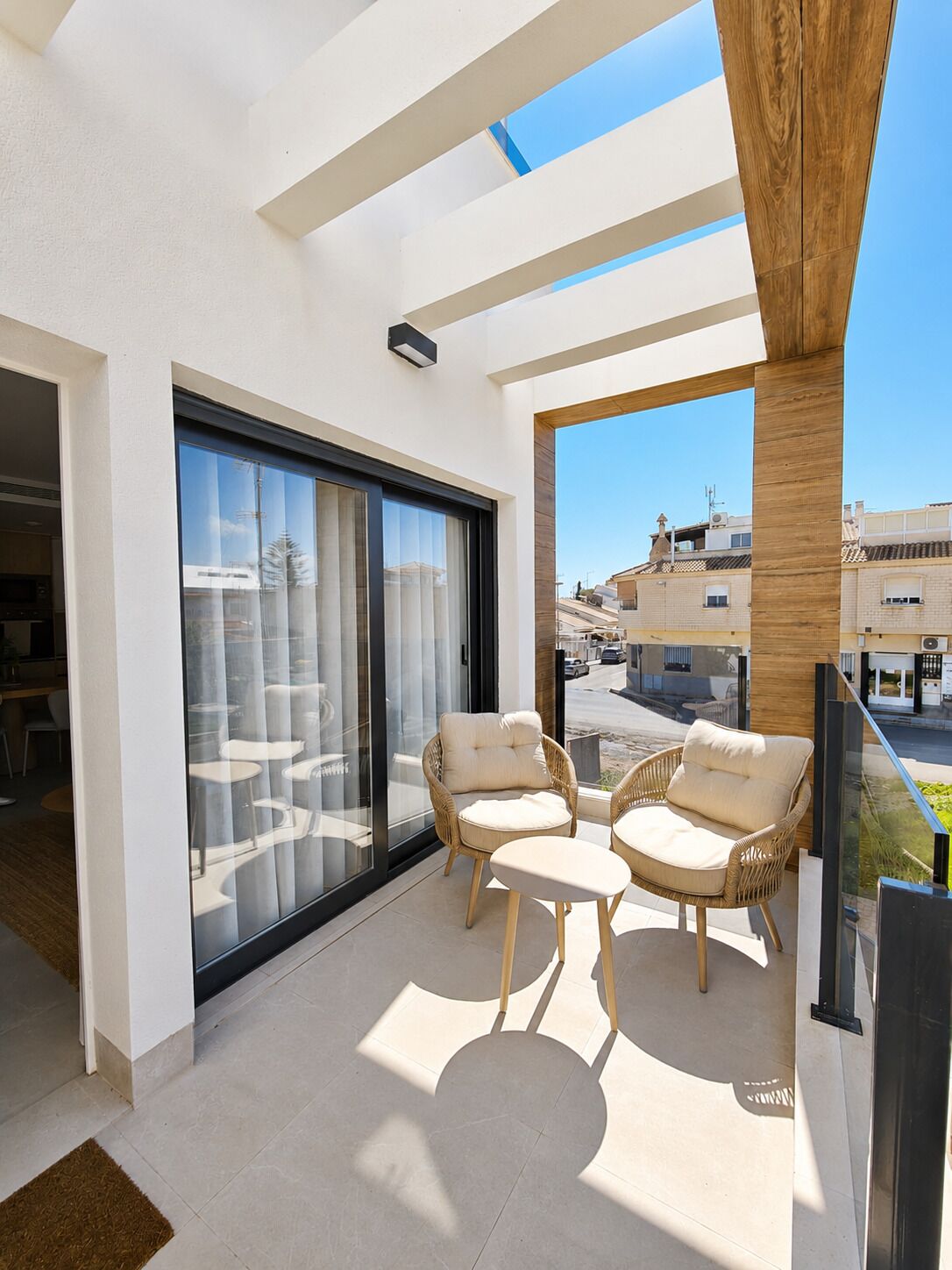 A balcony with a glass door, wicker furniture, and a view of the street.