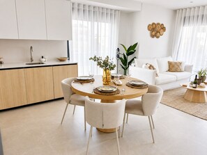 A modern kitchen with a dining area, white cabinetry, and a round table set for four. - Casa Aruna | Private Pool & Rooftop Terracel (San Pedro del Pinatar)