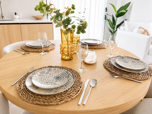 A round dining table set with plates, cutlery, and glasses, surrounded by woven placemats and a decorative vase with greenery. - Casa Aruna | Private Pool & Rooftop Terracel (San Pedro del Pinatar)