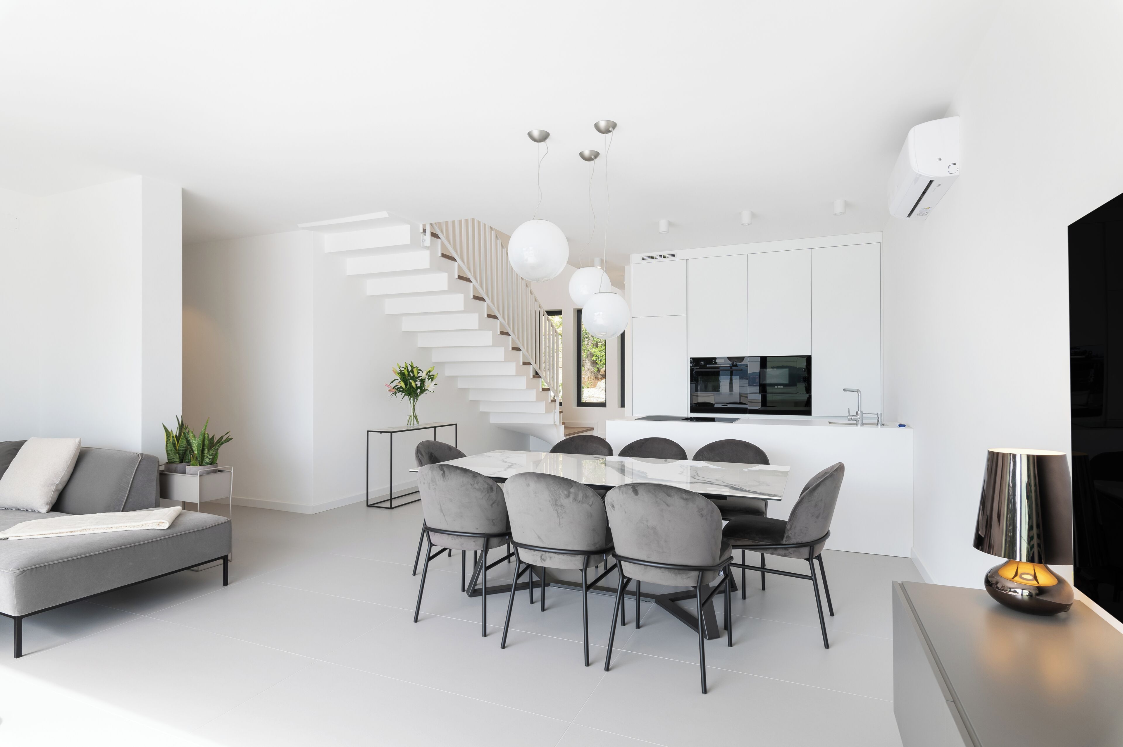 A modern living space with a staircase, dining area, and kitchen.