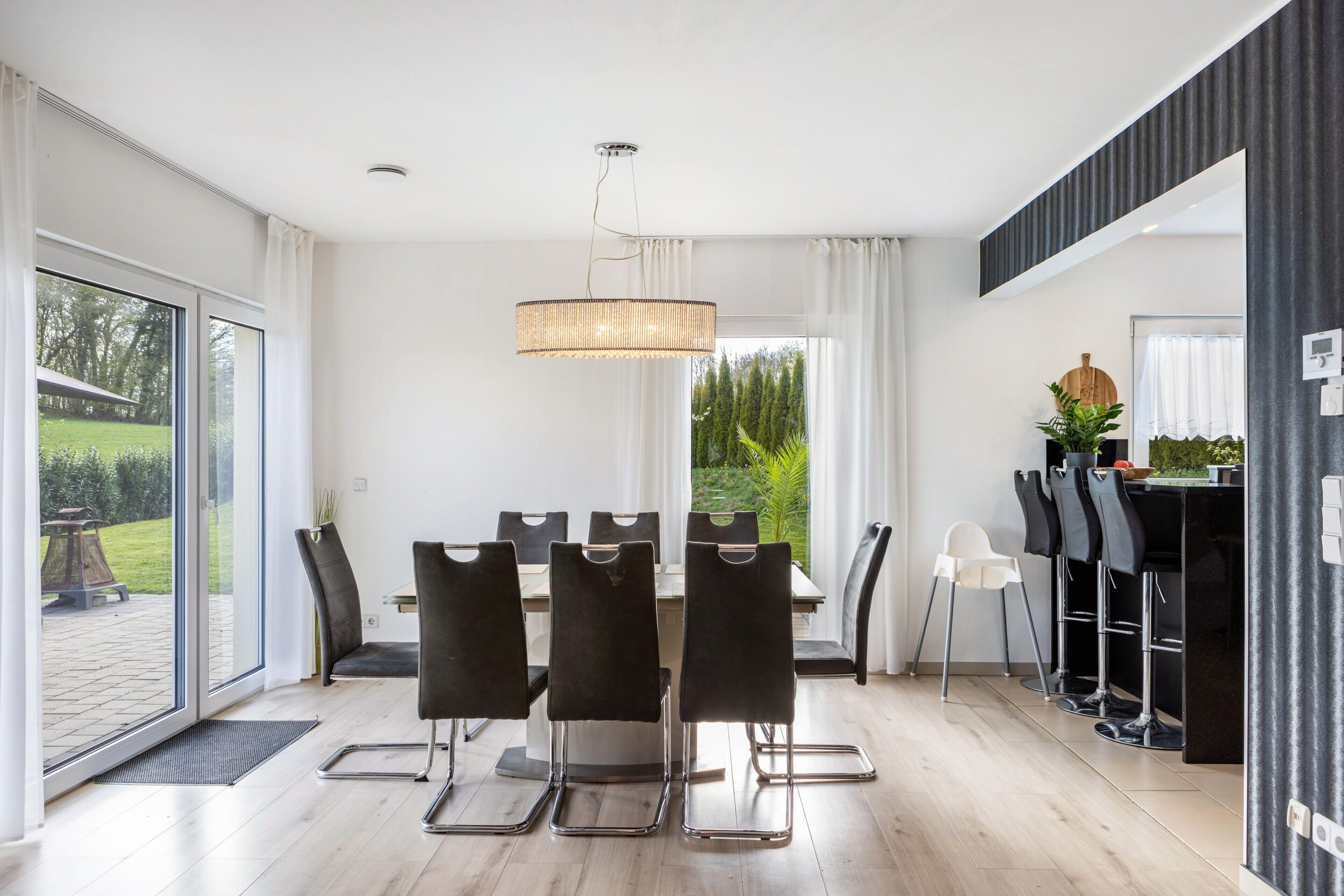 Un comedor moderno con una mesa y sillas, una lámpara colgante y vistas al exterior.