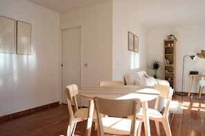 Un coin repas avec une table ronde et des chaises, un canapé, une bibliothèque et un lampadaire.