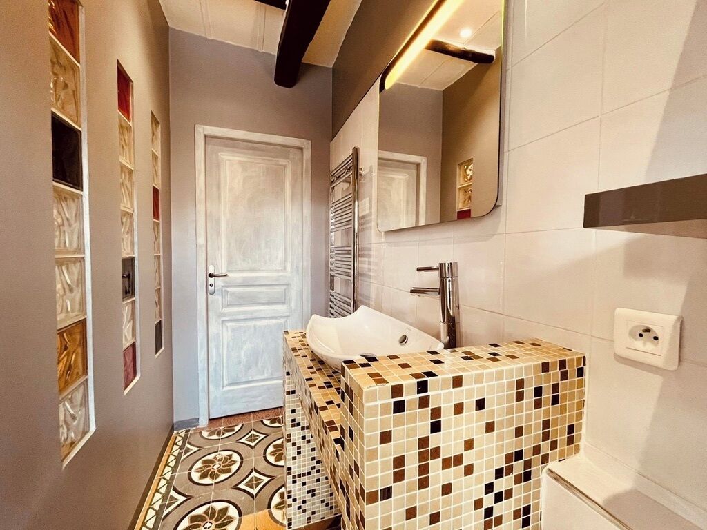 Une salle de bain avec un lavabo carrelé, un miroir et une porte.