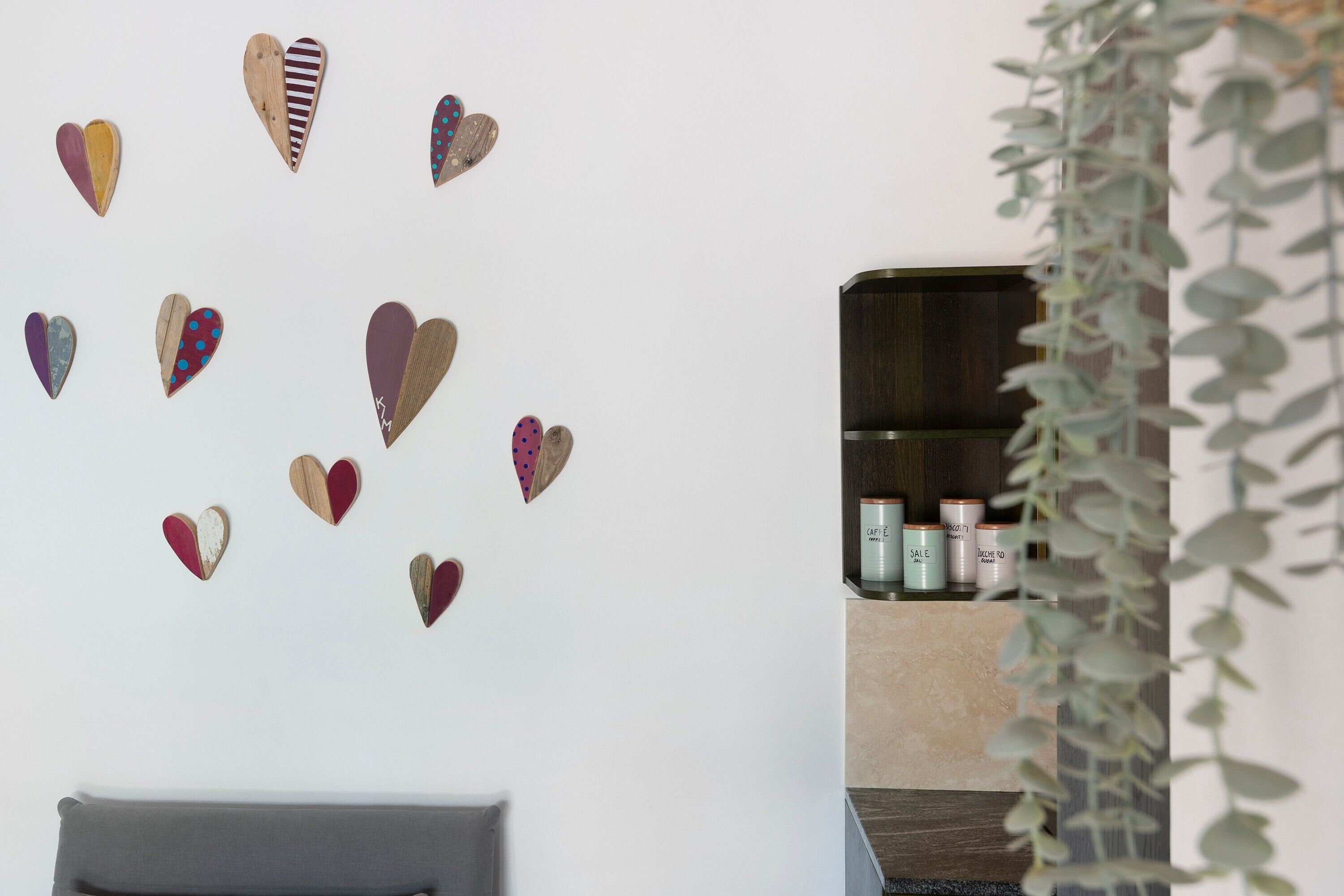 Una habitación con una pared decorada con objetos con forma de corazón, un estante con productos para el cuidado de la piel y una planta.
