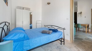 A bedroom with a bed, a wardrobe, a desk, and chairs. - Holiday Home 'Kim' with Private Garden, Wi-Fi and Air Conditioning (Capoliveri)