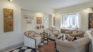 A living room with a checkered floor, a sofa set, a coffee table, and wall-mounted artwork. - Alaya Stays Chalet Vie 3 BHK Villa (Kasauli)