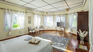 A room with a bed, a TV, a wooden cabinet, and a dining table with teapots. - Alaya Stays Chalet Vie 3 BHK Villa (Kasauli)