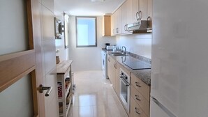 Een smalle keuken met een inbouwoven, een spoelbak en een raam.